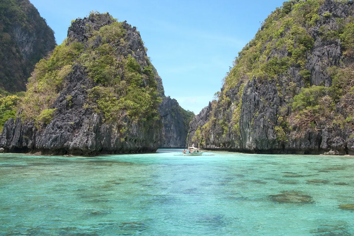 A turquoise lagoon between limestone cliffs in Bacuit Bay, El Nido