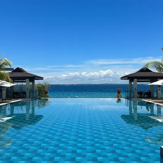 Crimson's infinity pool running out towards the sea between two pavilions